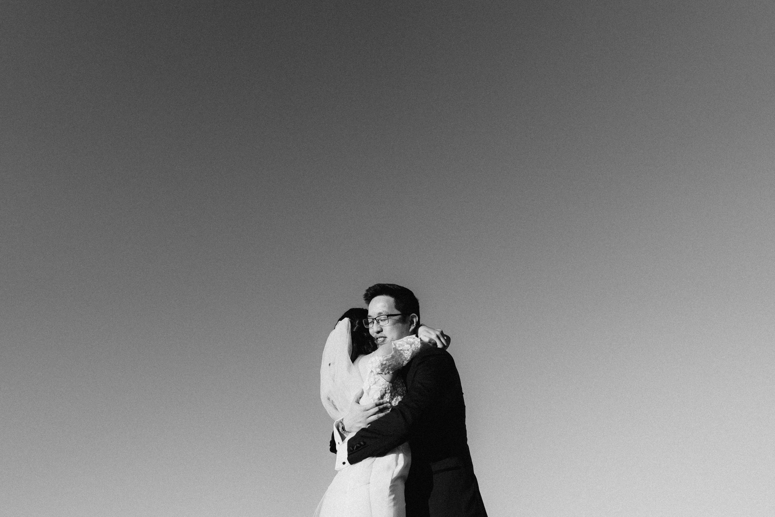 A loving embrace between two figures silhouetted against a minimal black and white sky.