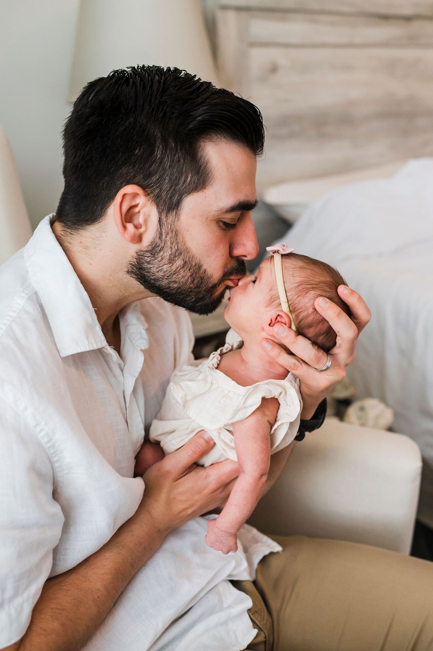 A series of intimate family moments captured on a white bed showing affection and connection.