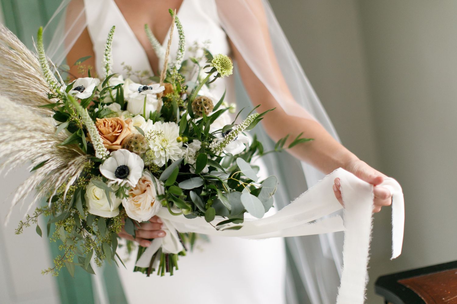 Elegant white and green floral wedding bouquets with delicate pampas grass accents.