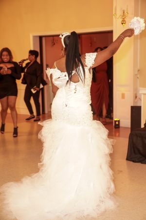 Bride in a flowing white ballgown twirls gracefully during a wedding dance.