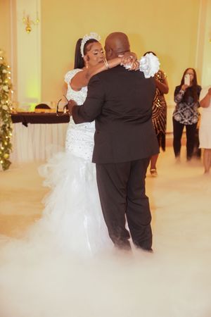 A couple performs their first dance at a wedding amid soft yellow lighting and romantic atmosphere.