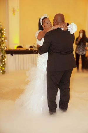 Elegant couple sharing their first dance at a wedding reception with warm amber lighting.