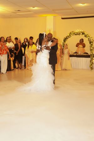 A couple shares their first dance at a wedding reception while guests look on from the sidelines.