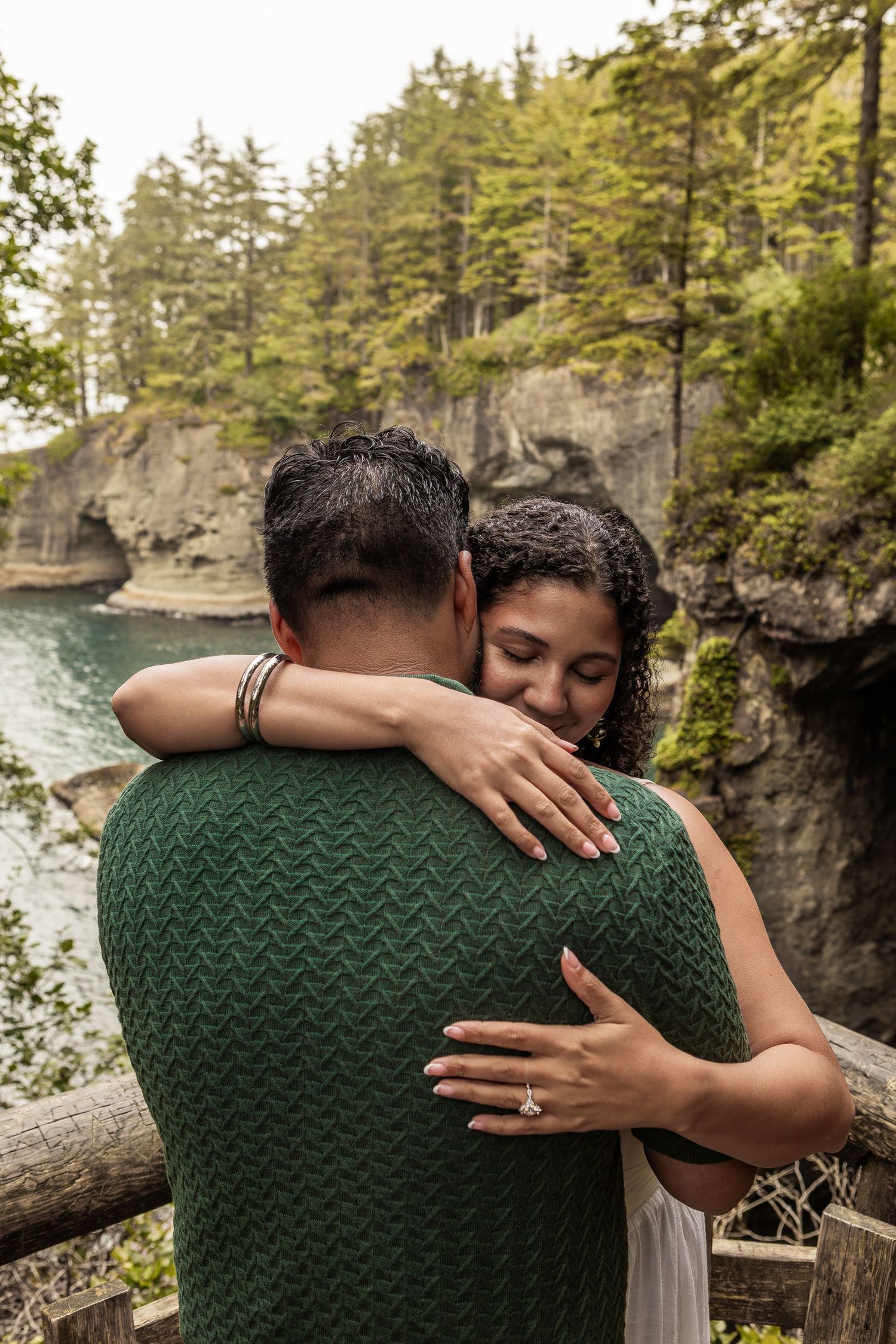 Intimate embrace captured against dramatic cliffside wilderness backdrop.