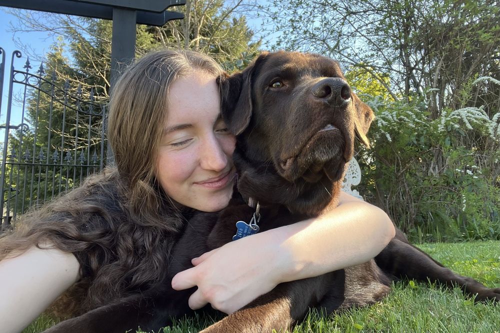 Katie Phillips (Soulfull Photographs) the photographer hugging her dog, a chocolate lab, in the grass