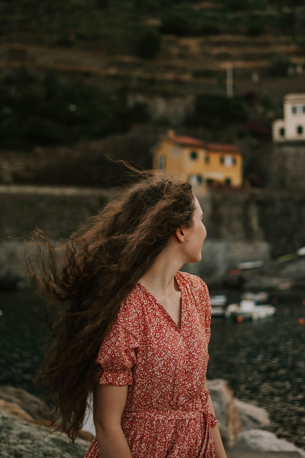 Katie Phillips (Soulfull Photographs) the photographer in a red dress in Italy looking at the beautiful houses by the beach