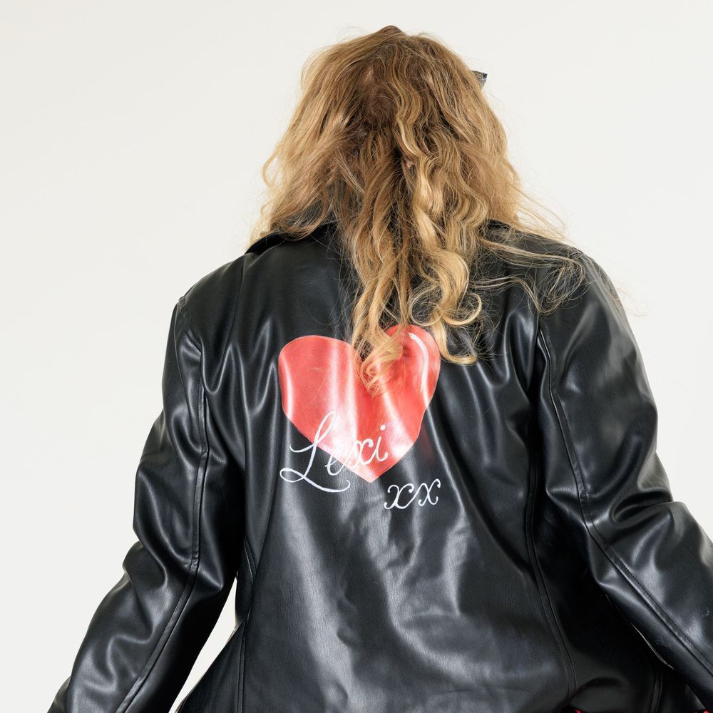 Model wearing a black leather jacket with a heart design, showcased in a pinup photoshoot setting.
