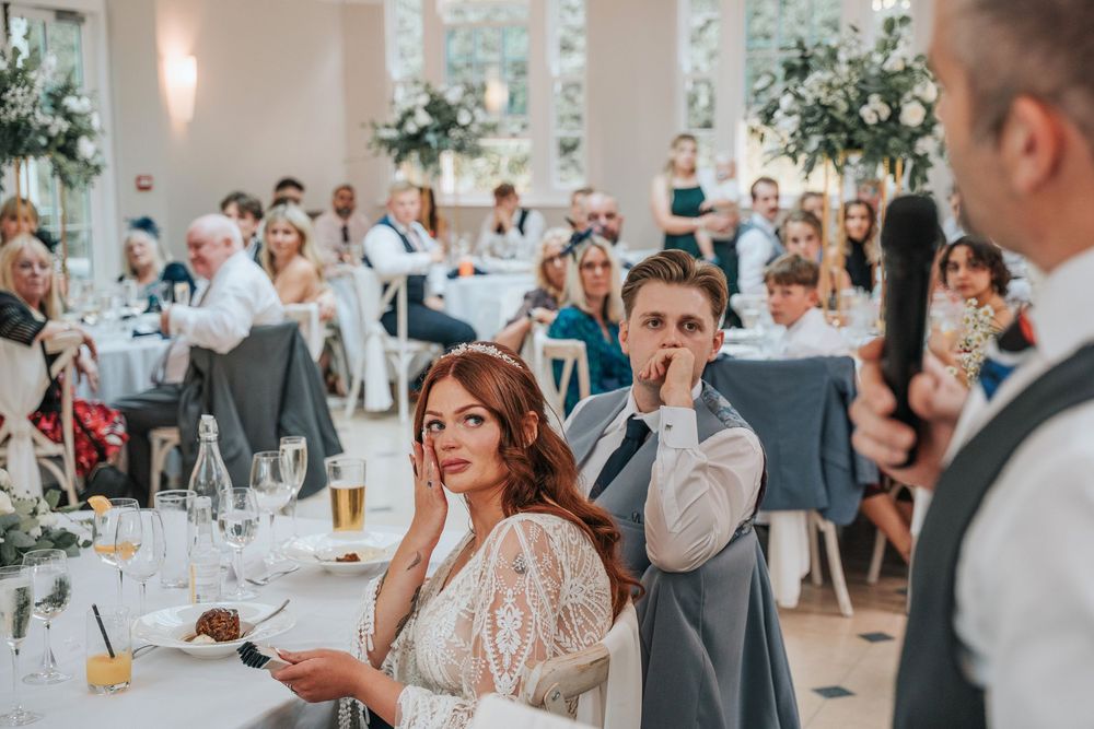 Bride wiping away tears during emotional wedding speech at Rockbeare Manor