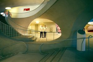Modern architectural interior with curved staircase and dramatic lighting.