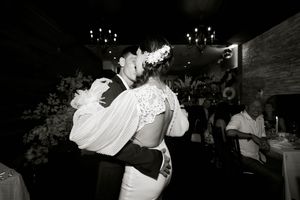 Wedding reception guests dancing and celebrating in dimly lit venue.