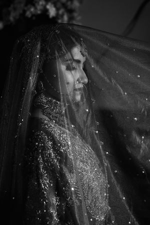 Sparkling veil detail shot with scattered crystals catching light against a dark background.