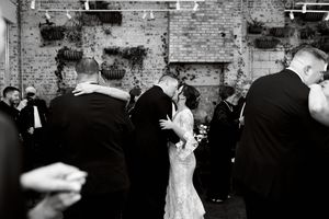 Wedding guests dancing and mingling in front of exposed brick wall at reception.