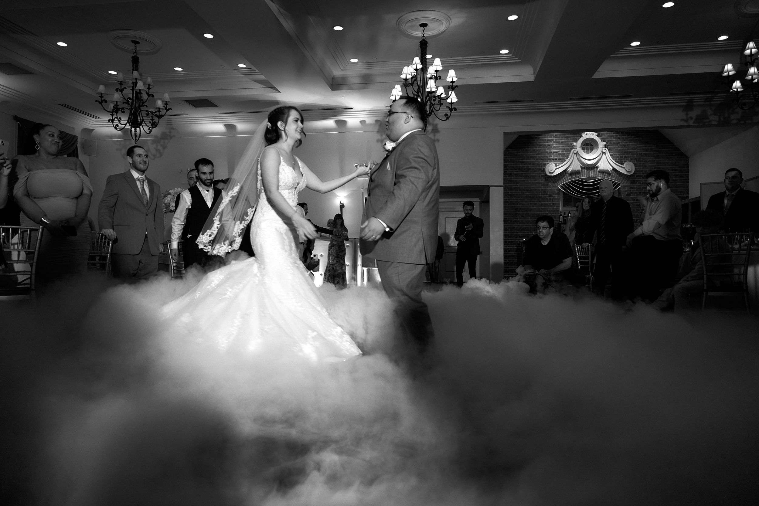 Wedding reception dance captured in dramatic black and white with low lighting effects.