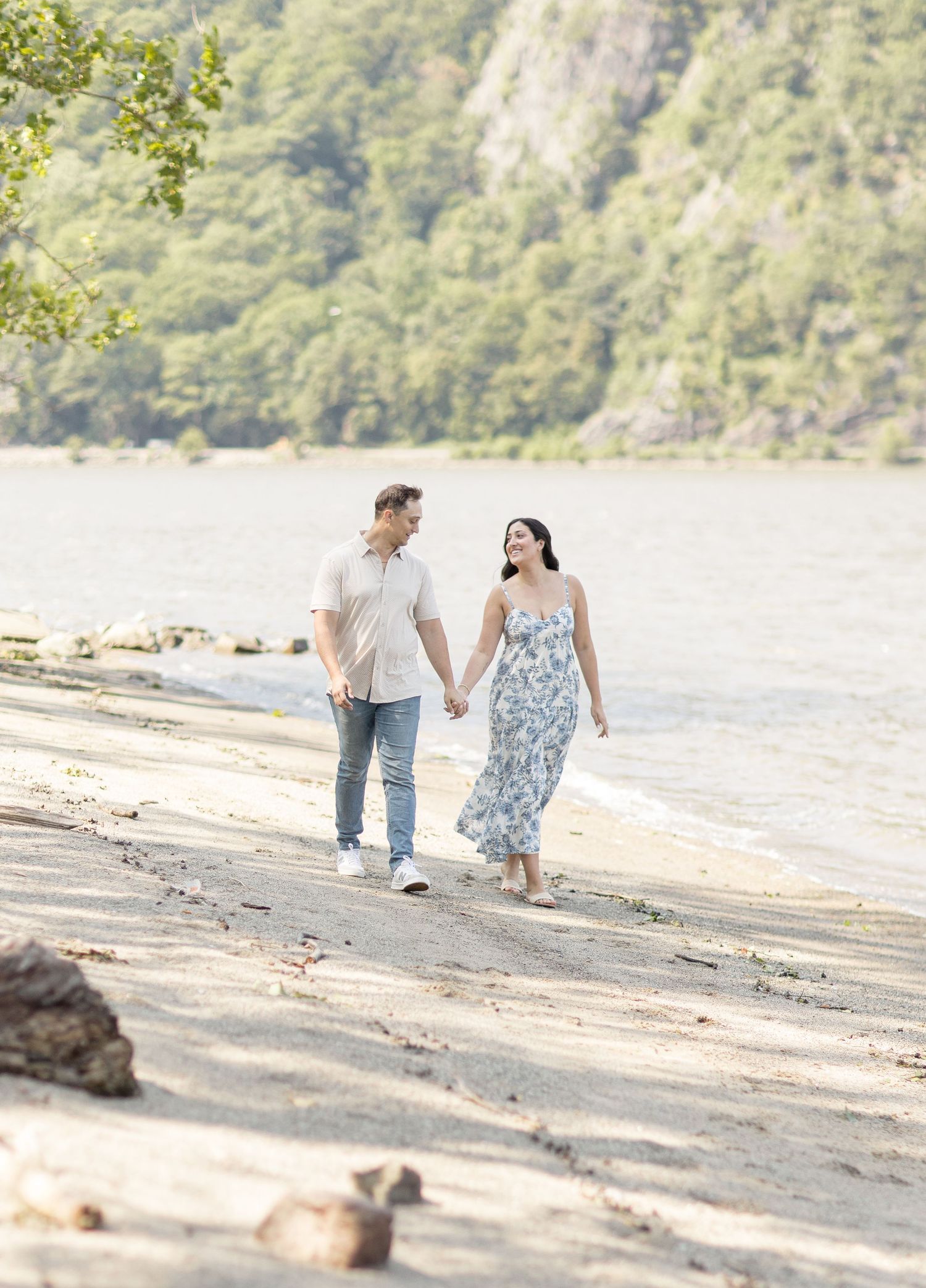 A couple embraces outdoors in a romantic pose against a soft blurred natural background.