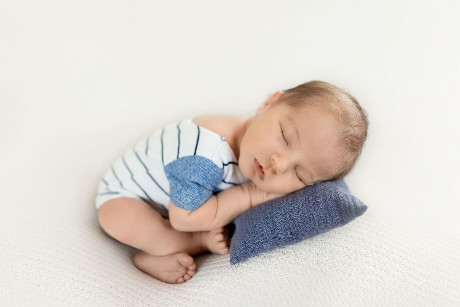Sweetly sleeping baby in light blue outfit lying on white backdrop in minimalist setting. Photos by Tampa Photographer DigitalMyst Photograp