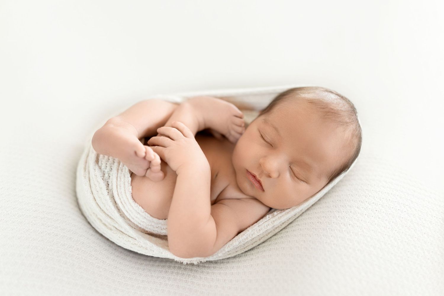 Peaceful sleeping newborn on white backdrop with soft neutral tones and gentle lighting. Photos by Tampa Photographer DigitalMyst Photograph
