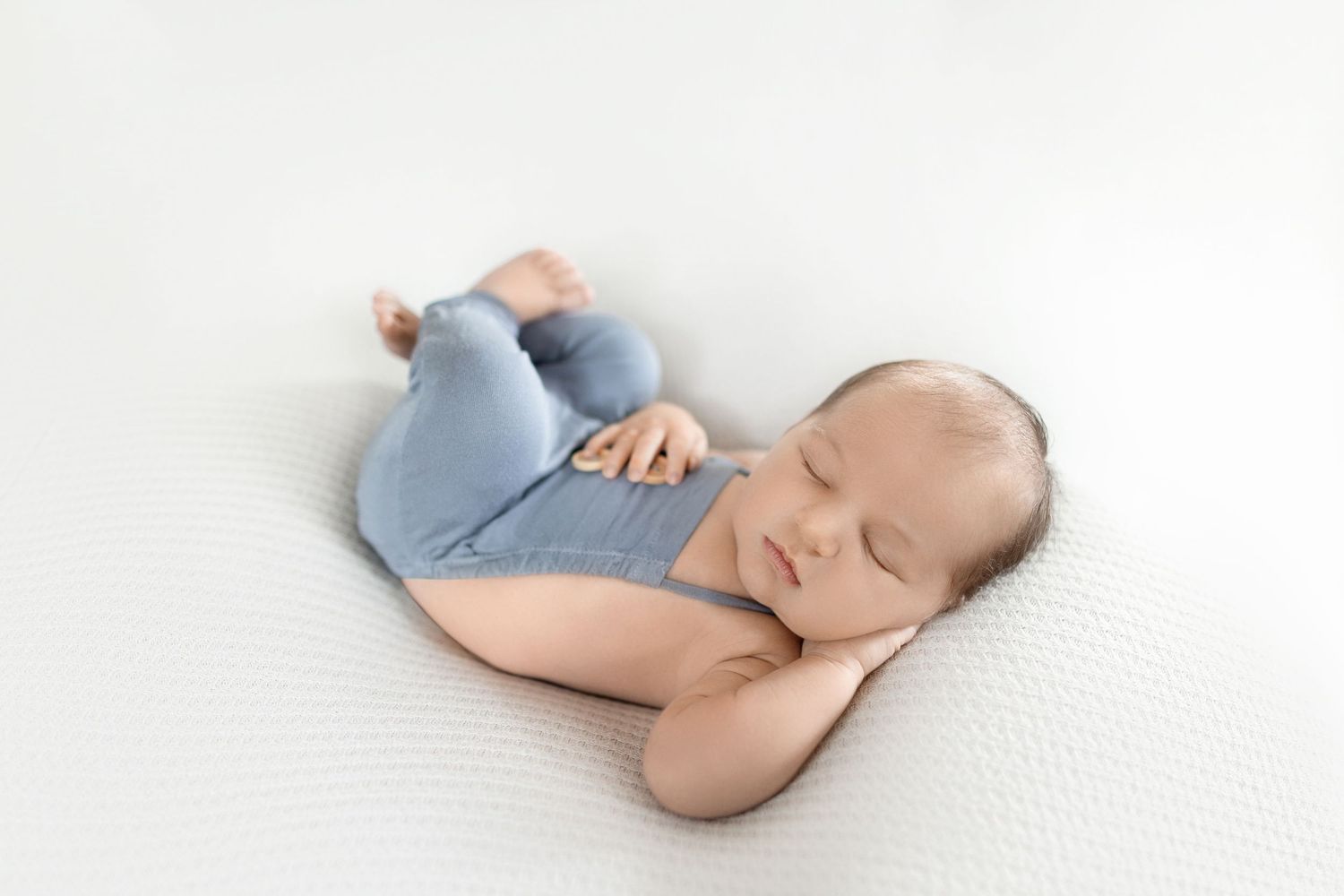 Sleeping newborn wearing soft blue clothing on white background in studio setting. Photos by Tampa Photographer DigitalMyst Photography