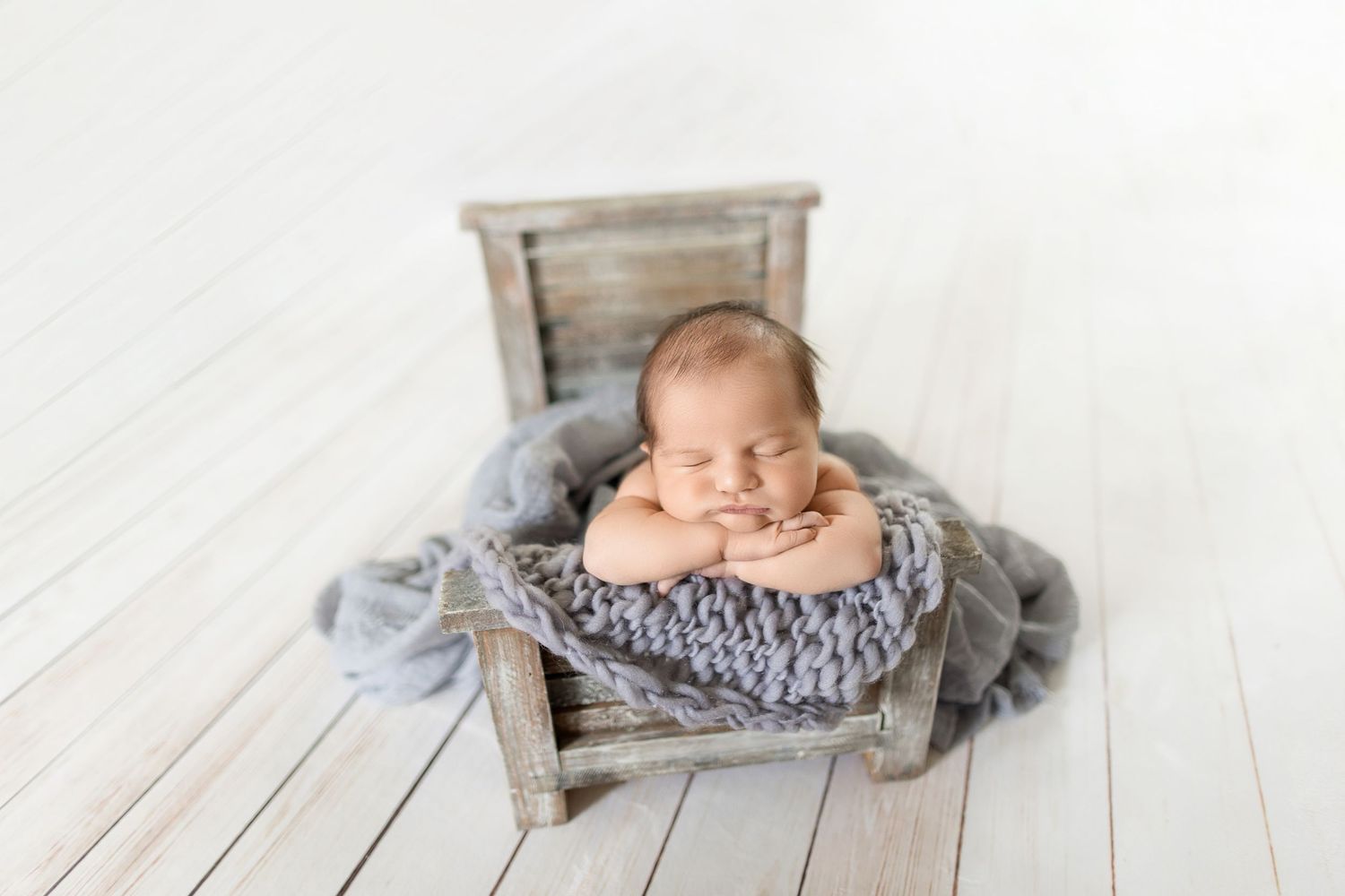 Sleeping newborn nestled in vintage wooden crate with soft gray blanket. Photo by Dani De La Rosa, DigitalMyst Photography, Wesley Chapel Fl