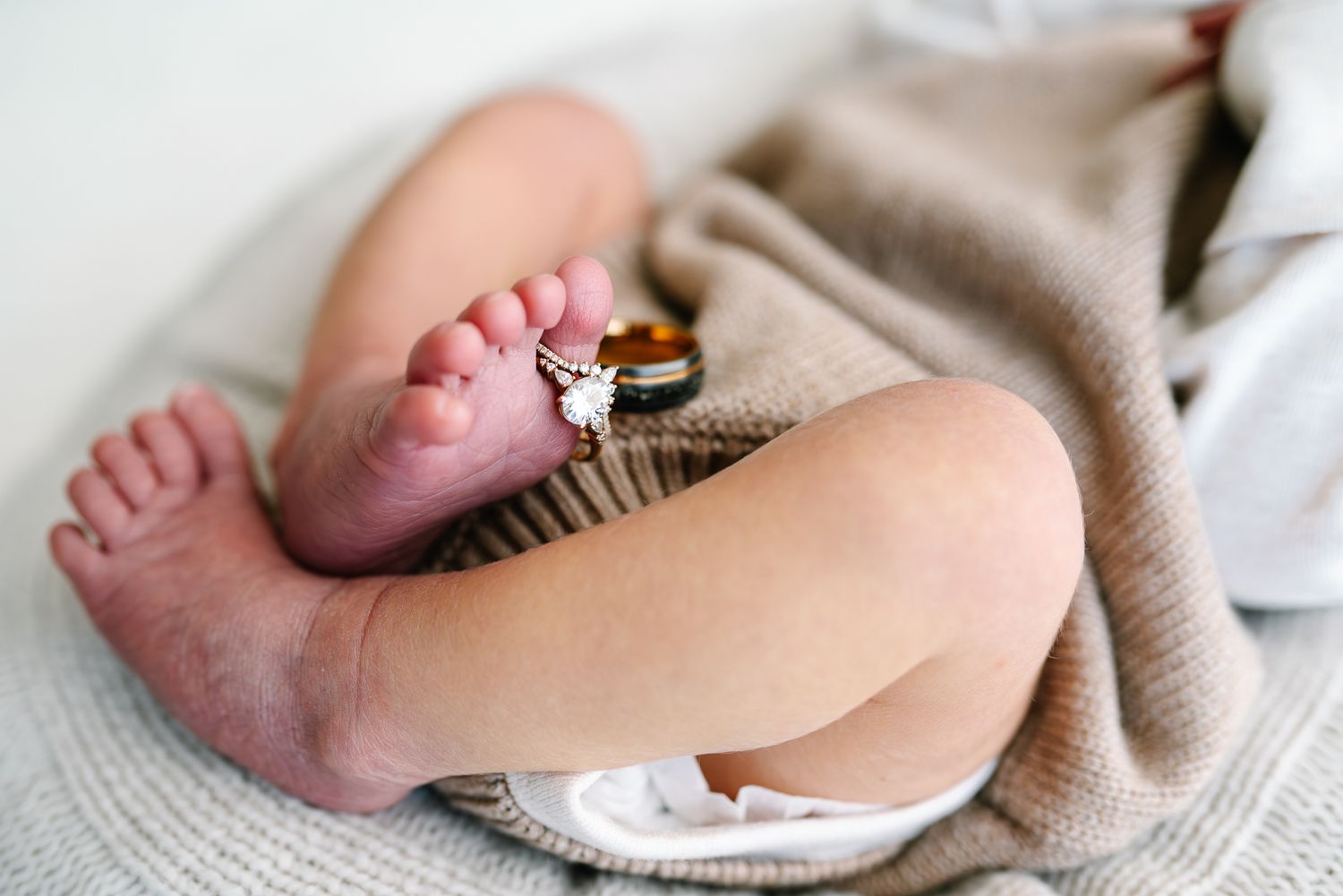 A baby in a beige outfit lies curled up on a soft white blanket while sleeping peacefully taken by Melbourne newborn photographer Pei A
