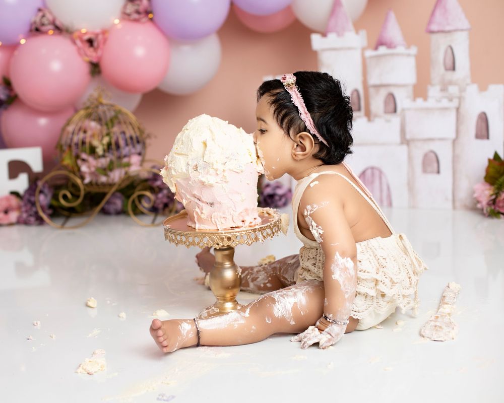 A first birthday cake smash session with pink and purple balloons and a castle-themed backdrop displaying multiple angles. boronia heights c