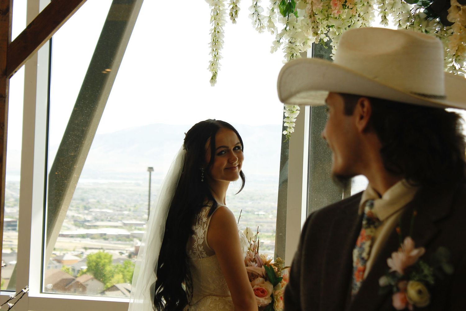 A bride and groom share a kiss at the altar, with floral decorations above.