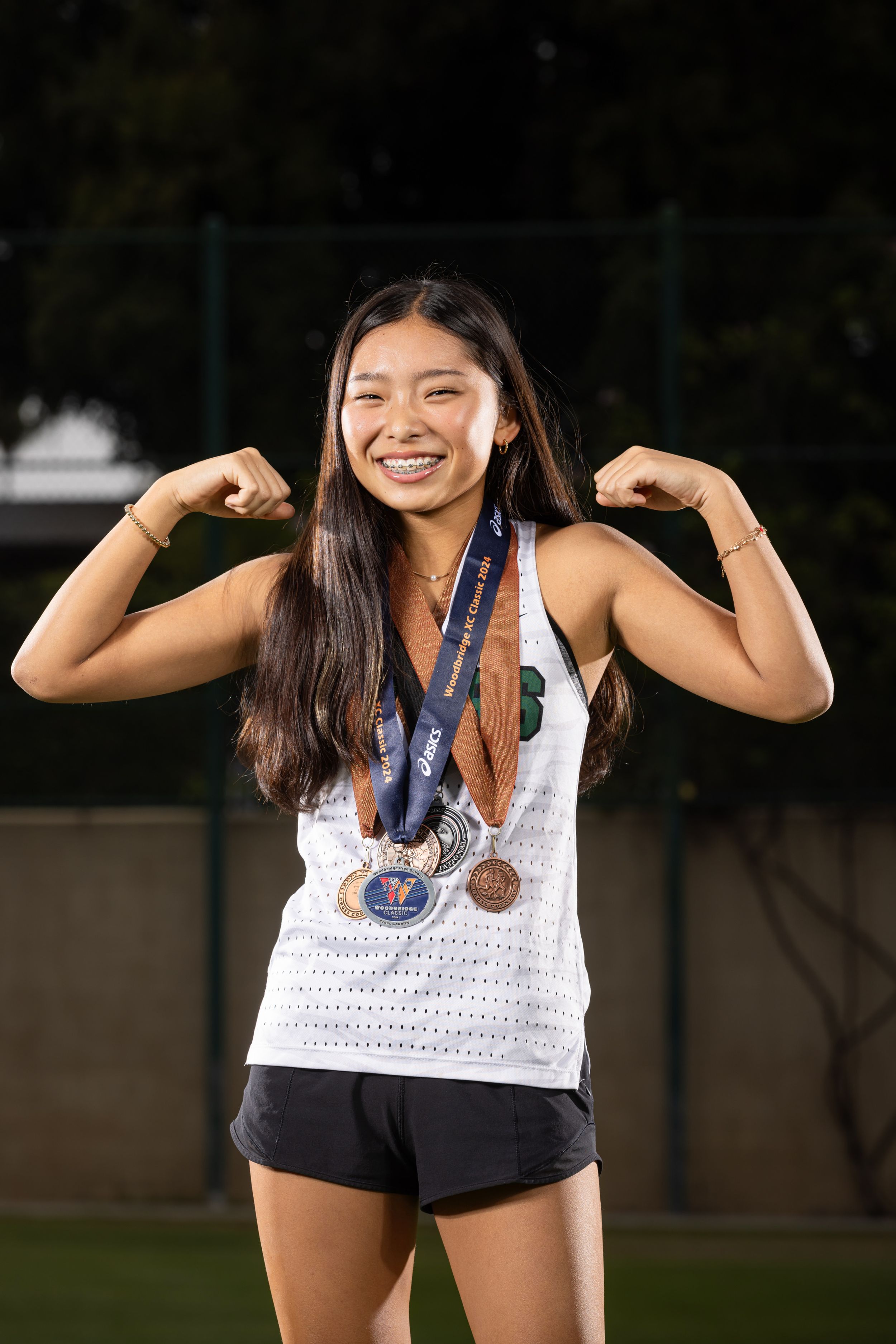 An athlete in athletic wear poses outdoors showing off their bronze medal with joyful expressions.
