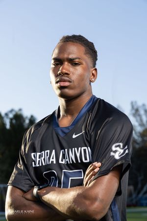 High school athlete poses in a black Serra Canyon Nike jersey against a bright sky background.