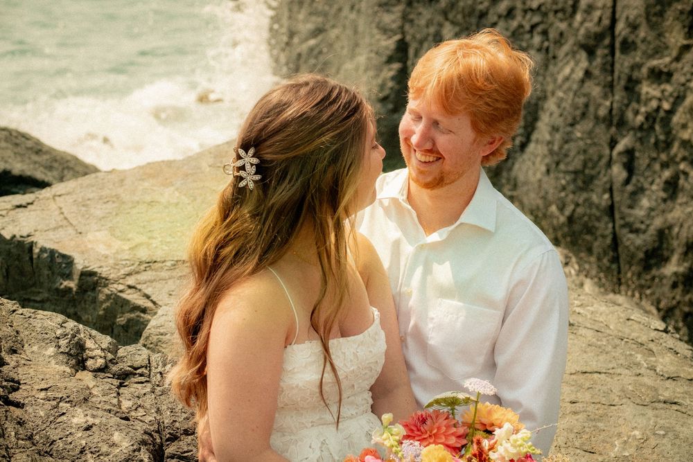 Two people share an intimate moment on a rocky coastline.