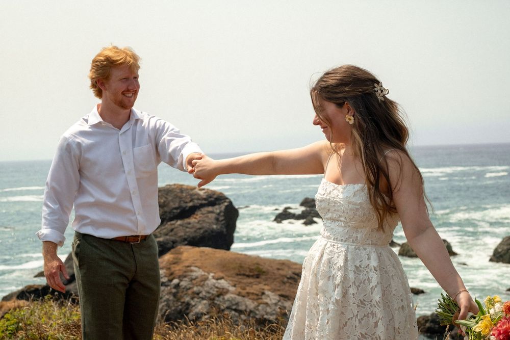 Two people enjoying a romantic moment on a coastal cliff with ocean waves in the background.