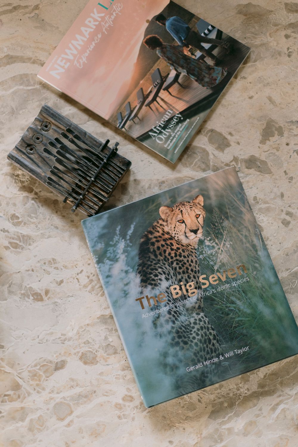 Safari books and a mbira instrument arranged on a marble surface, featuring The Big Seven wildlife photography book.