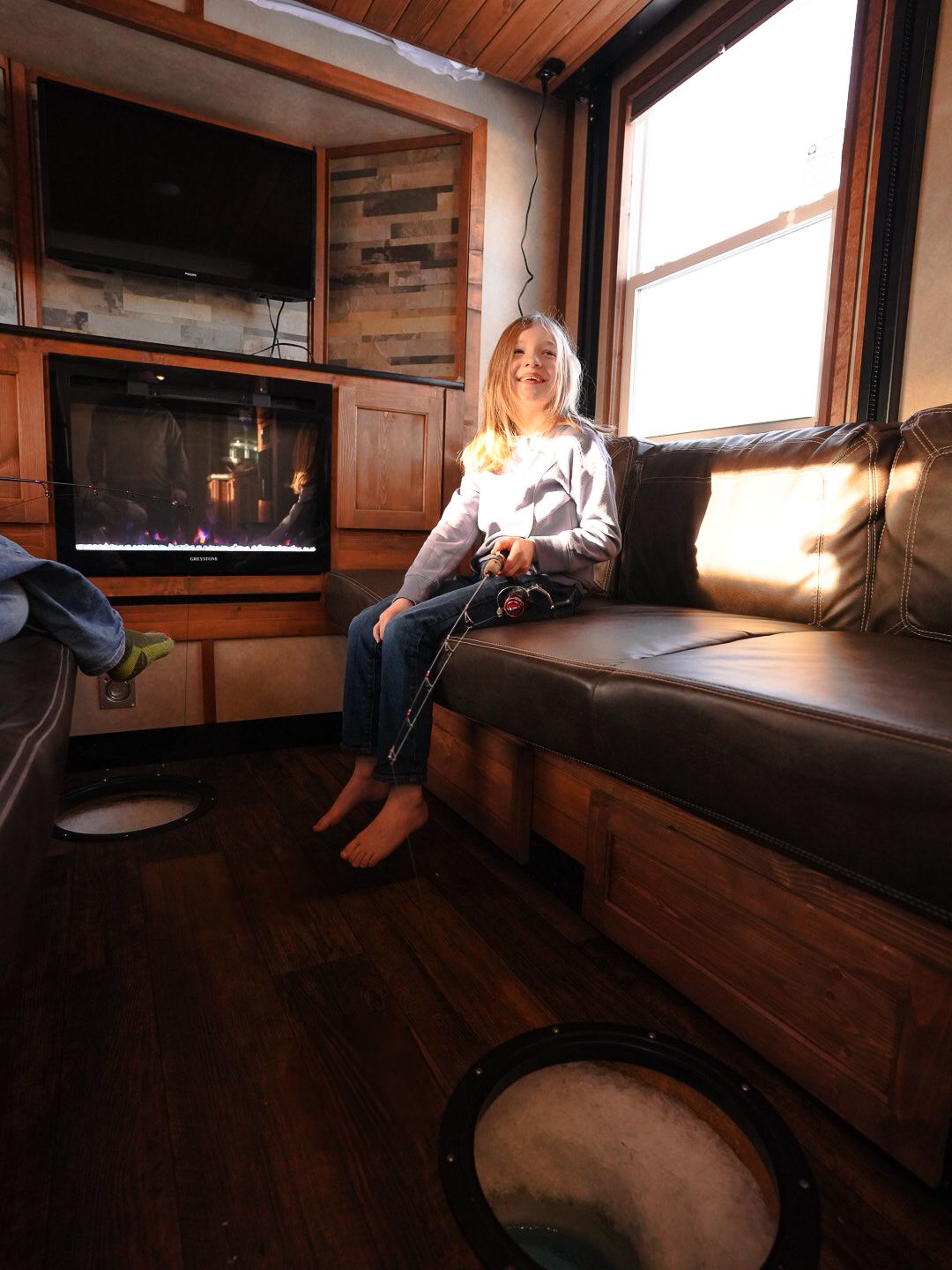 Sunlit RV interior with leather bench seating and wood paneling.