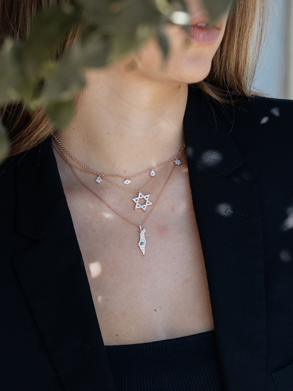A close-up view of delicate gold necklaces featuring Star of David, crystal and lightning bolt pendants on display.