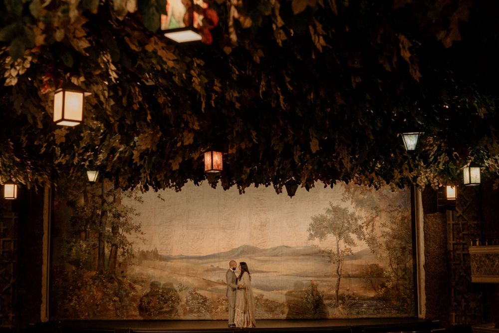 A romantic scene with hanging lanterns illuminating a couple beneath a whimsical tree canopy at dusk.