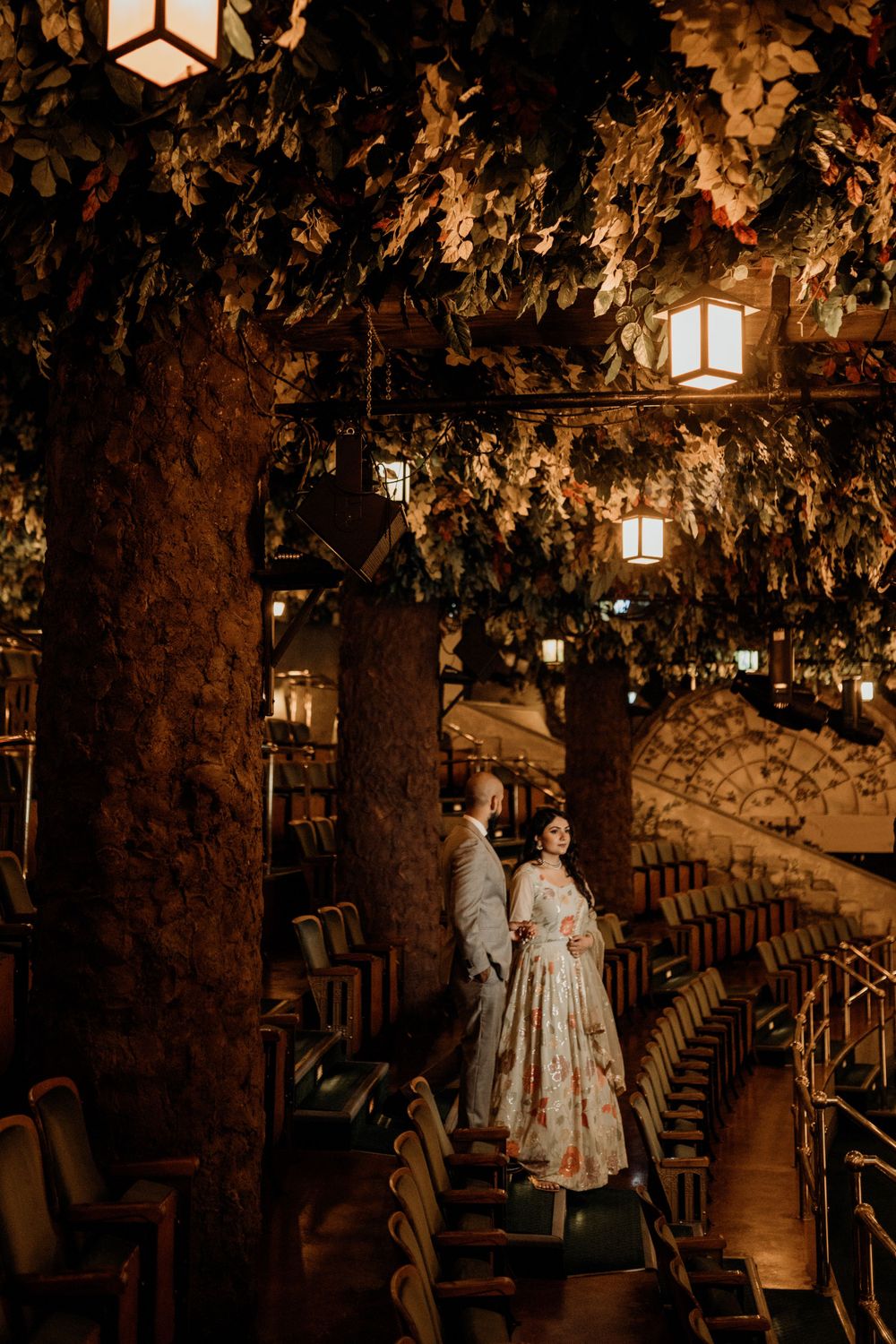 A dimly lit vintage theater interior with warm lantern lighting and ornate decor casting atmospheric shadows over empty seats.