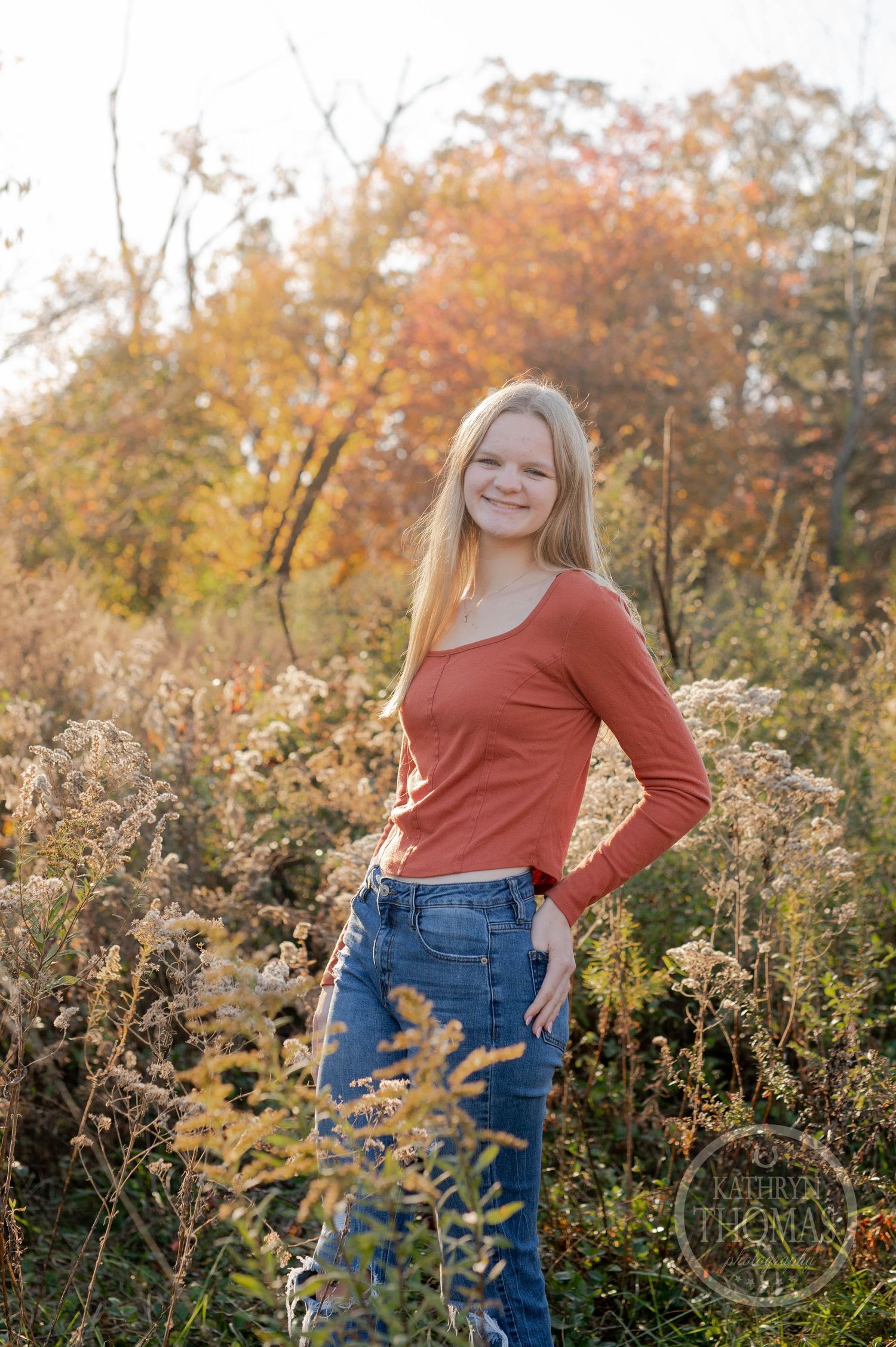Golden hour portrait in a field of dried wildflowers with autumn colors in the background.