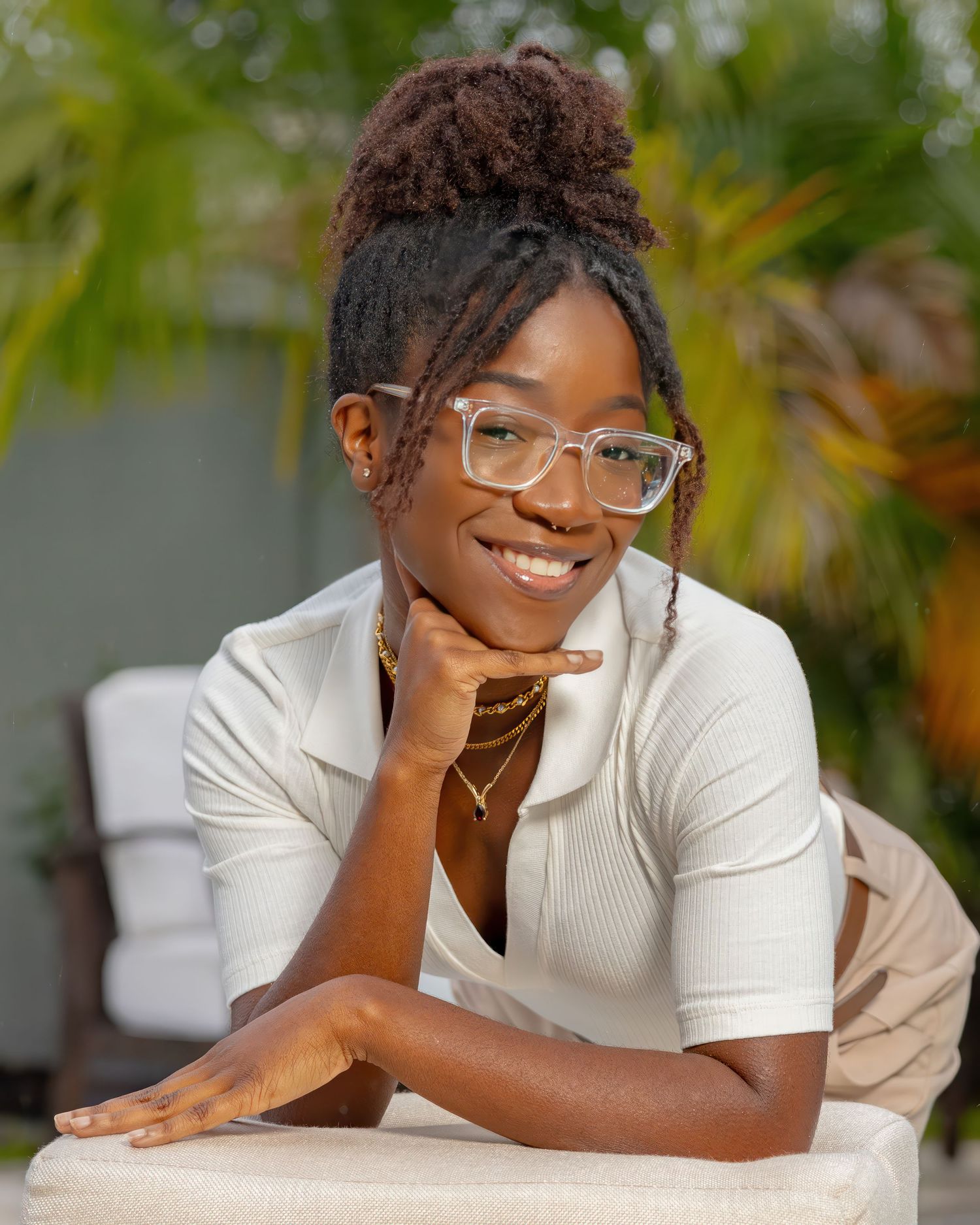 Professional portrait of person in white top and glasses with tropical background.