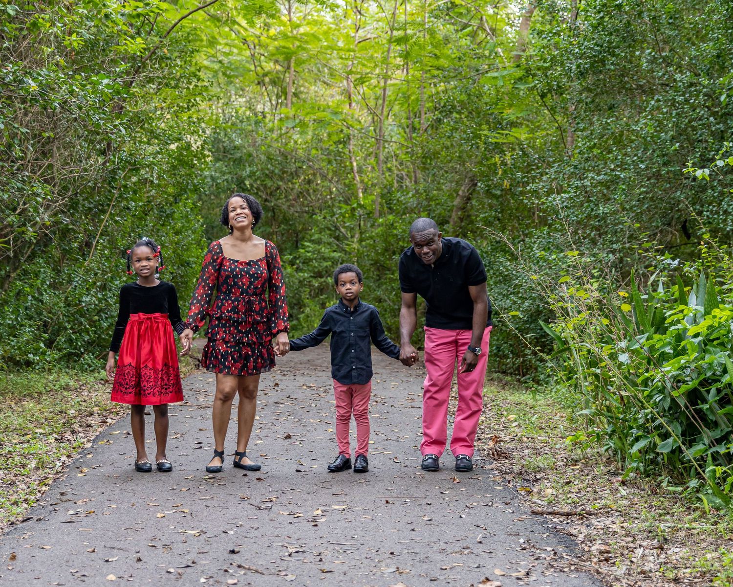 Family of four walking together on tree-lined nature path.