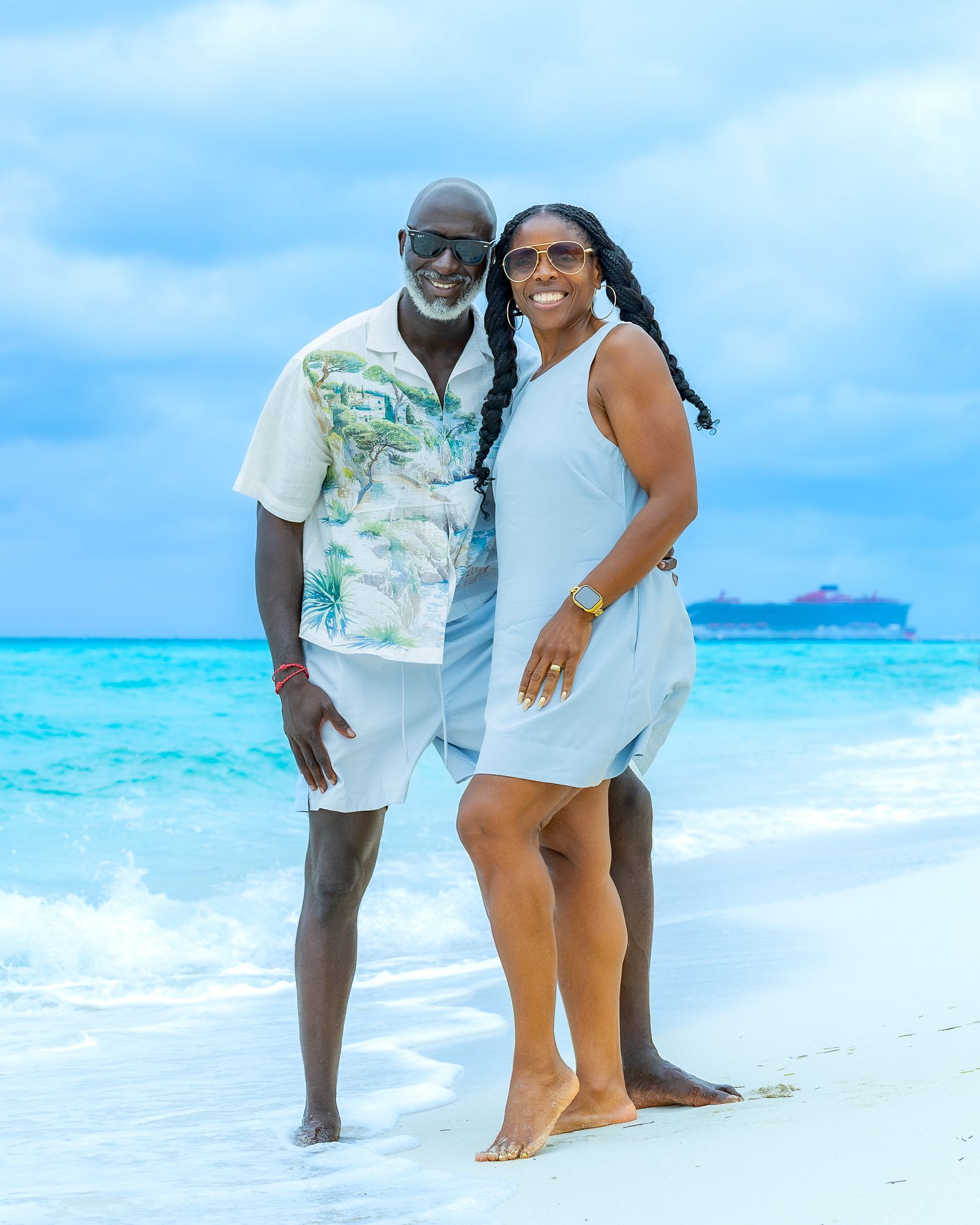 A couple shares a romantic moment on a pristine beach with turquoise waters and blue skies in the background.