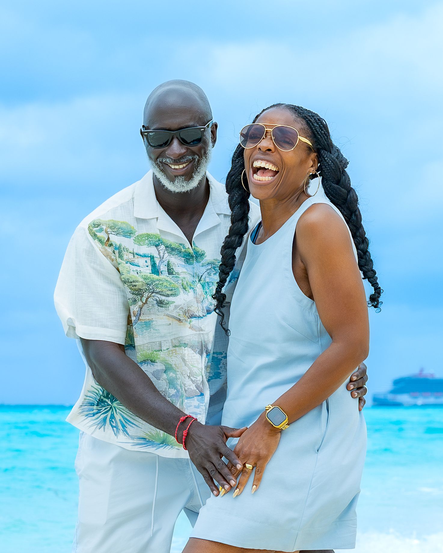A couple shares a joyful moment together on a beautiful tropical beach with turquoise waters and blue skies.