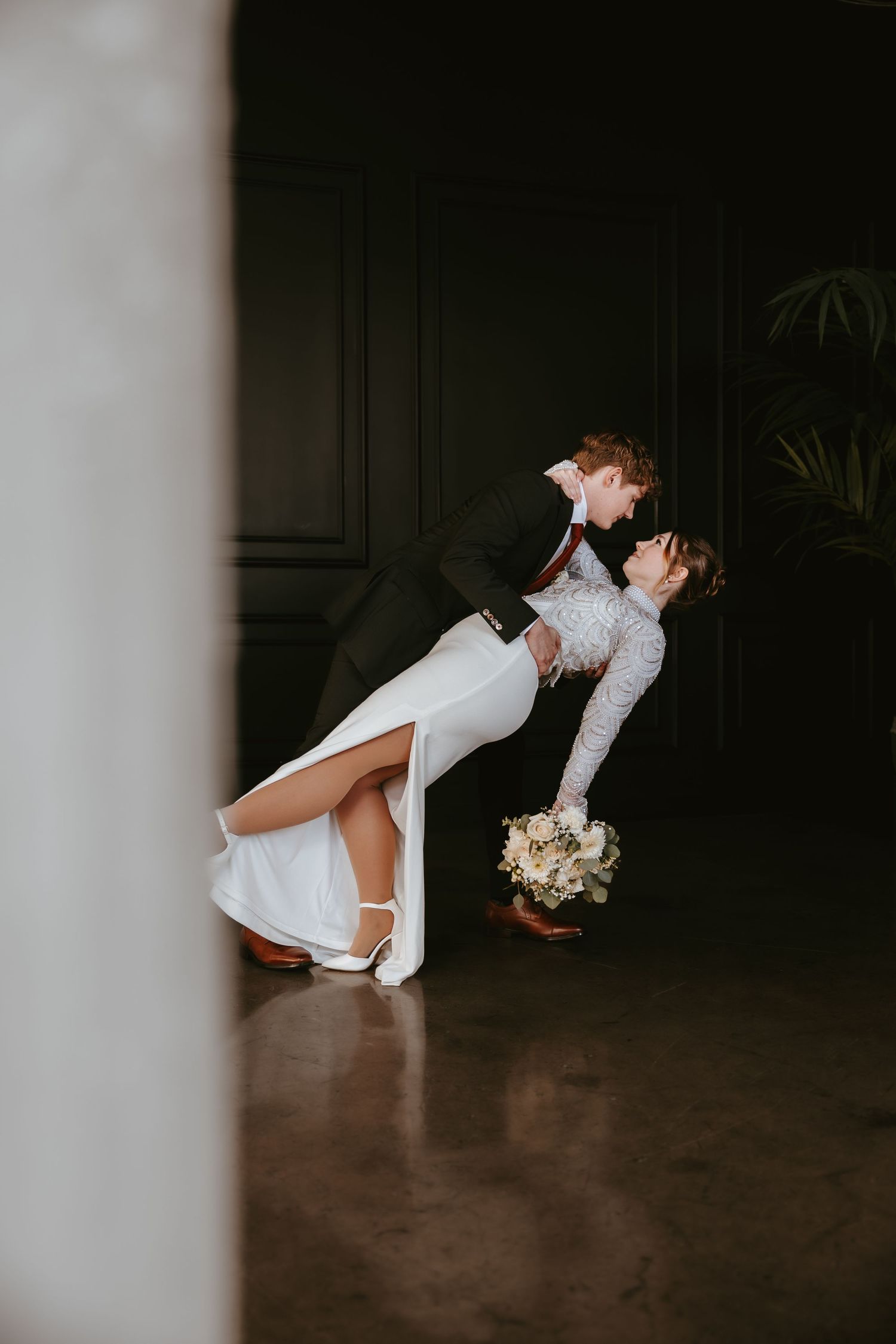 Dramatic wedding dip pose with bride holding bouquet.