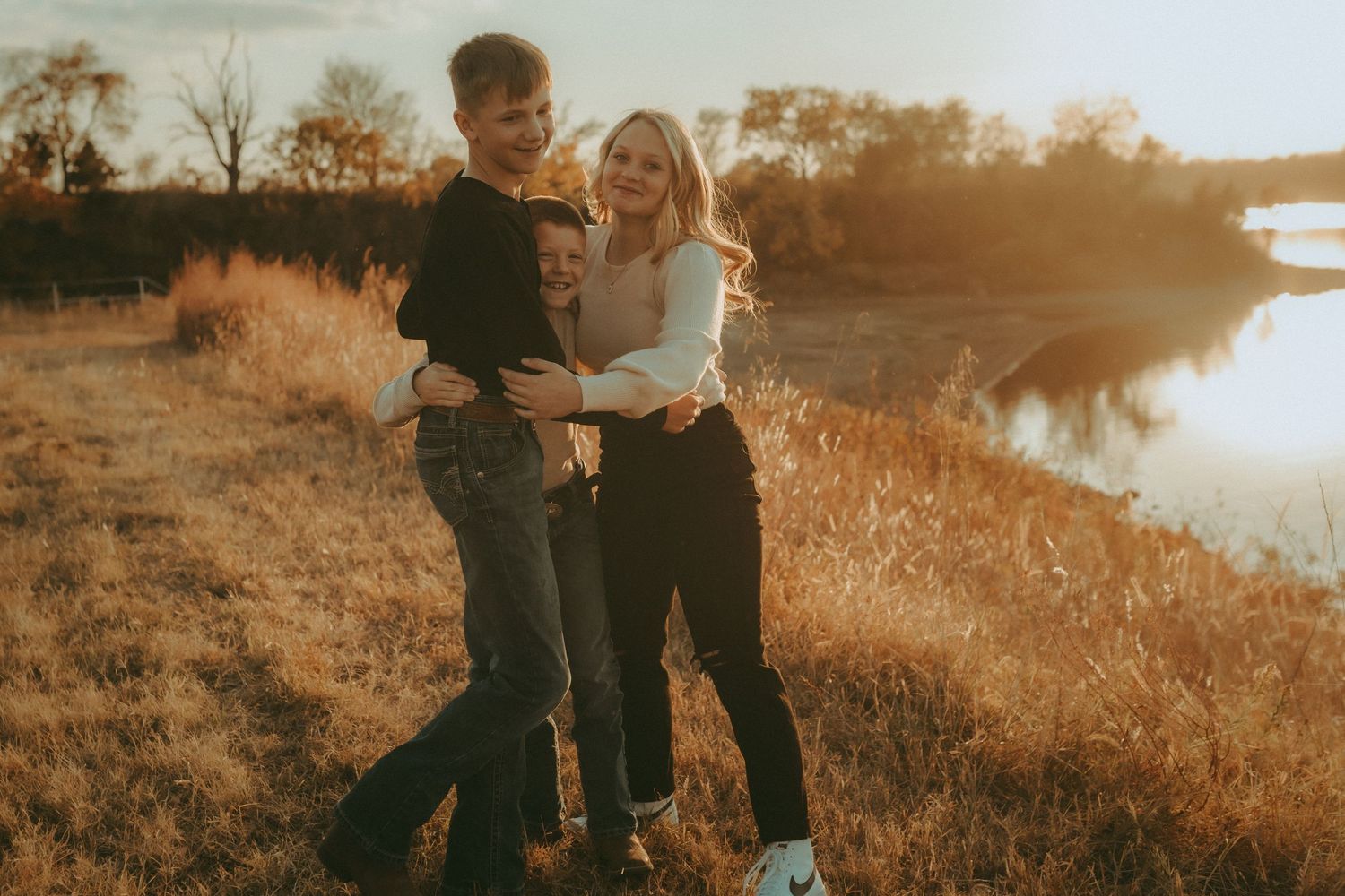 Family walking through Kansas field at sunset – lifestyle family photography by Kel Holliday