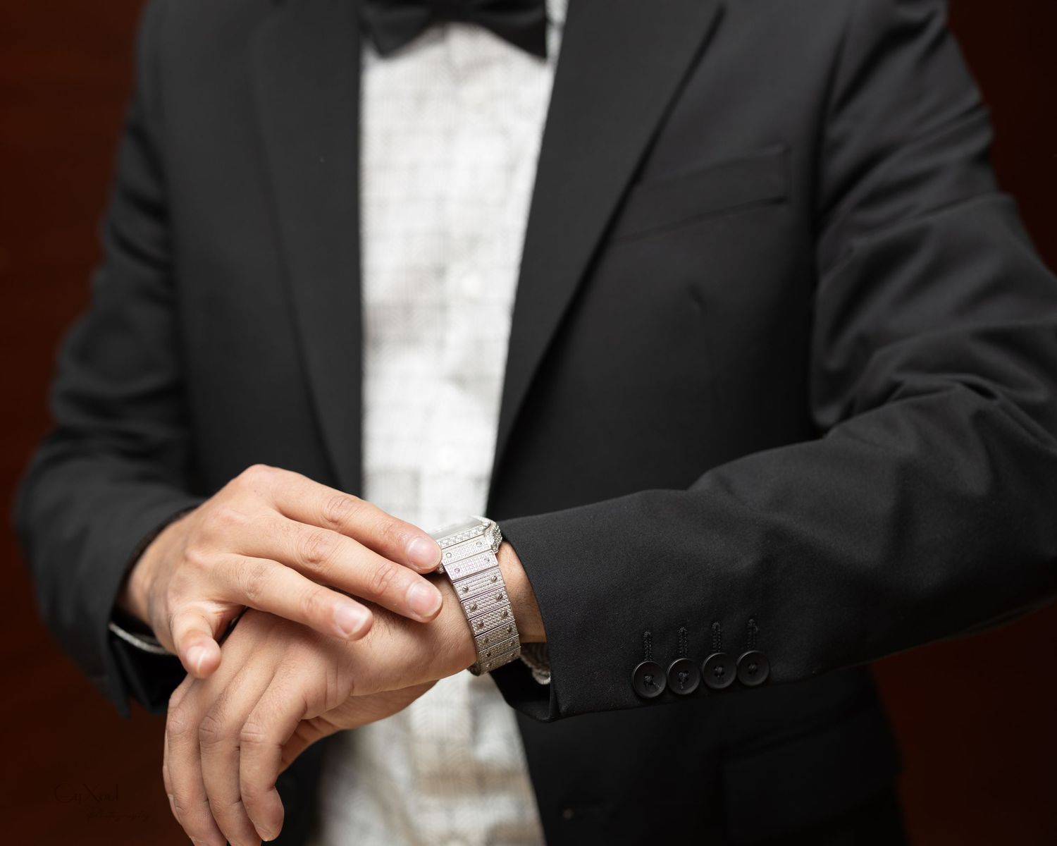 Detail shot of formal black tuxedo with silver watch on wrist.