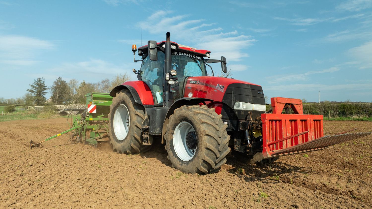 Red Case IH tractor pulling orange cultivation equipment across a freshly tilled field.