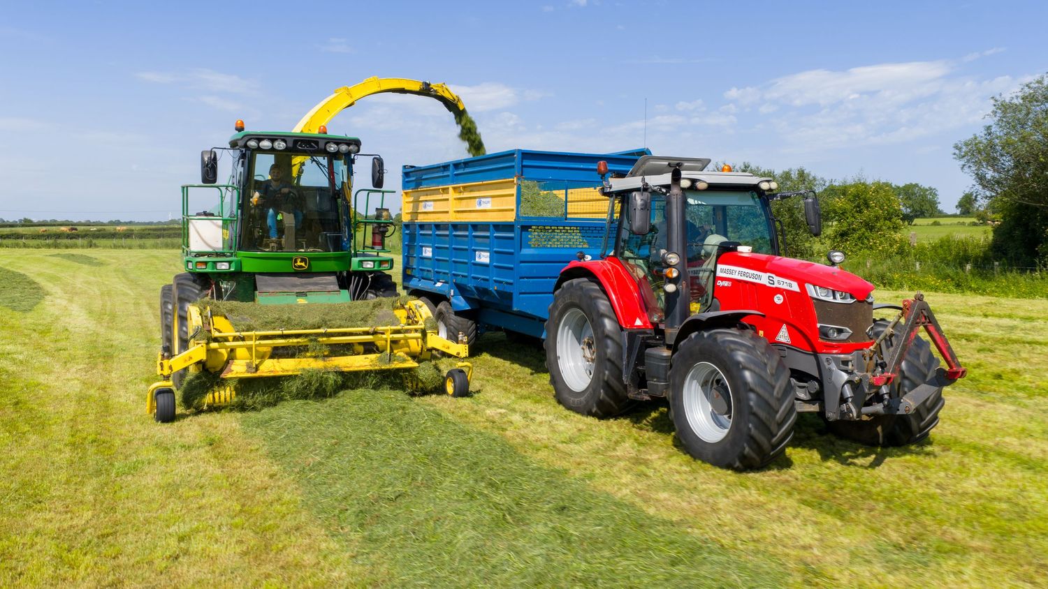 A row of modern agricultural equipment including tractors, balers, and harvesting machinery on green farmland under blue skies.
