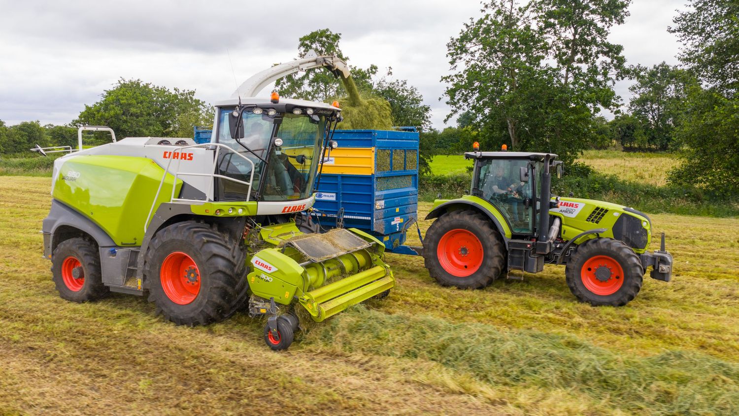 A line of modern tractors and farming equipment working together to harvest crops in a sunny agricultural field.