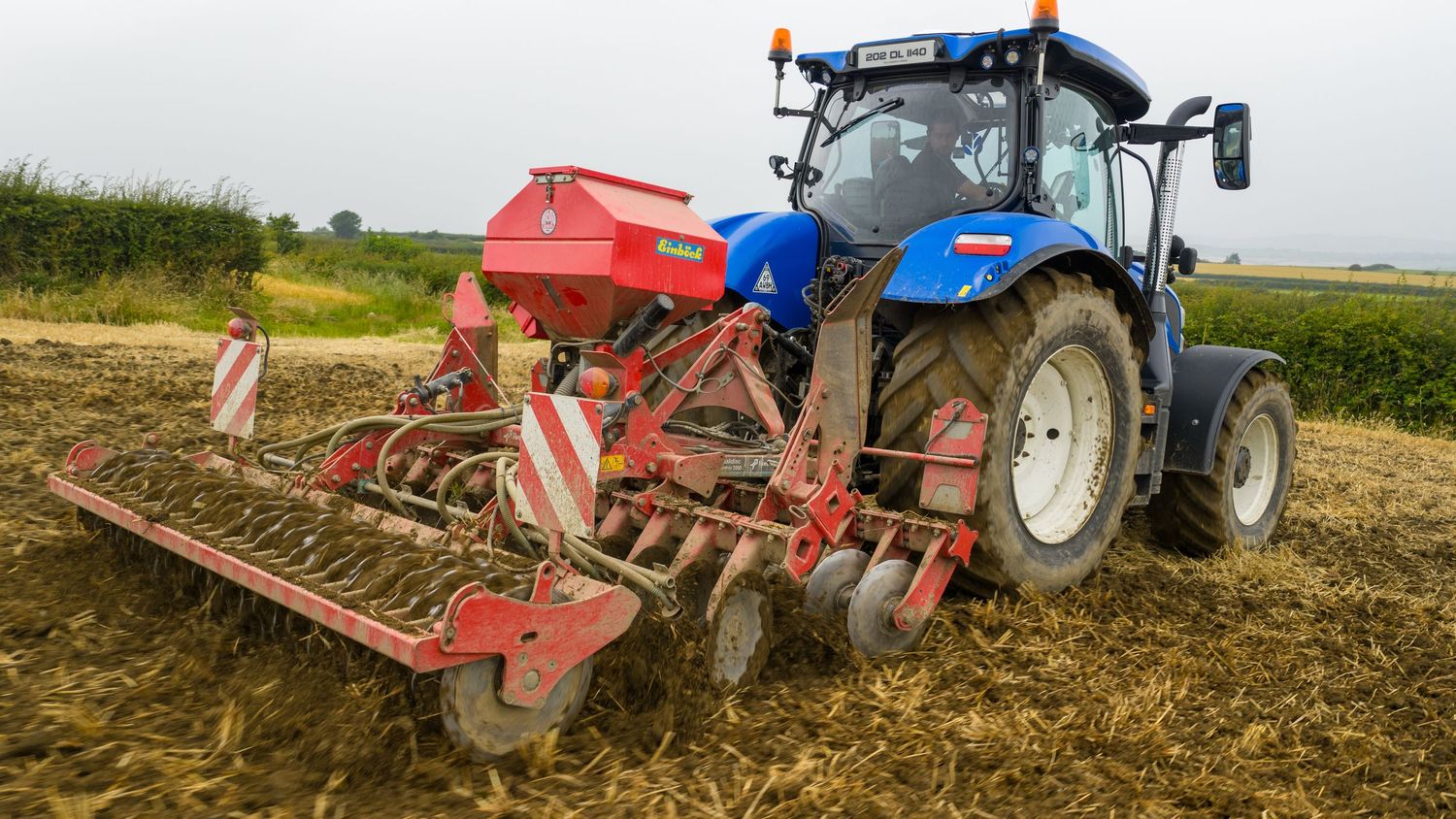 Farm tractors with attached plowing equipment working in agricultural fields during soil preparation.