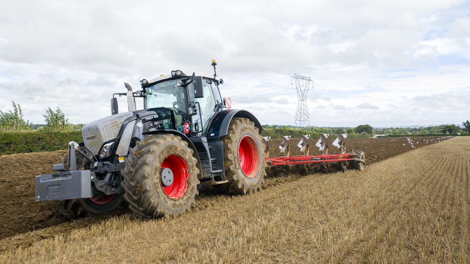 Modern tractor working in wheat fields at harvest time with rolling farmland stretching to horizon.