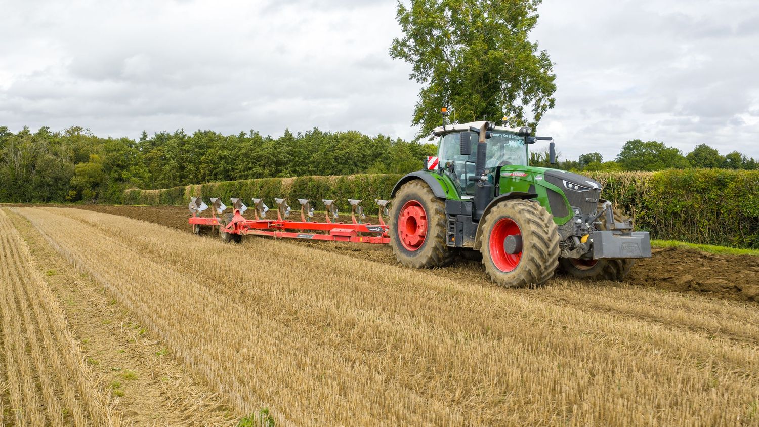 Panoramic view of farm fields showing combine harvesters and tractors working through golden wheat fields during harvest season.