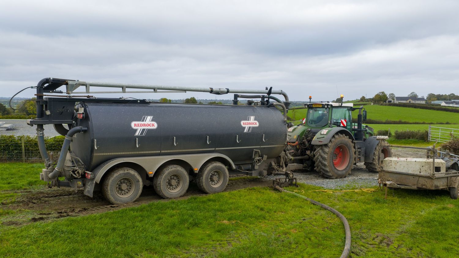 A panoramic view of agricultural equipment and storage tanks on a green rural farm field.