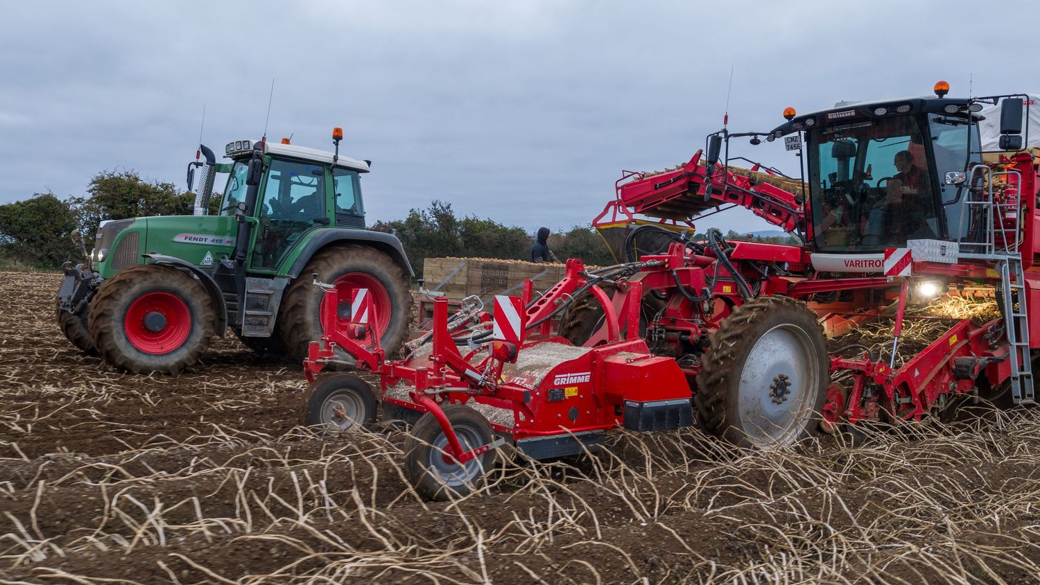 Modern agricultural machinery including tractors and plows working in a field during harvest season.